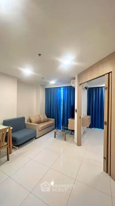 Modern living room with sleek furniture and blue curtains in a cozy apartment.