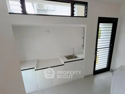 Modern minimalist kitchen with sleek white cabinetry and natural light.