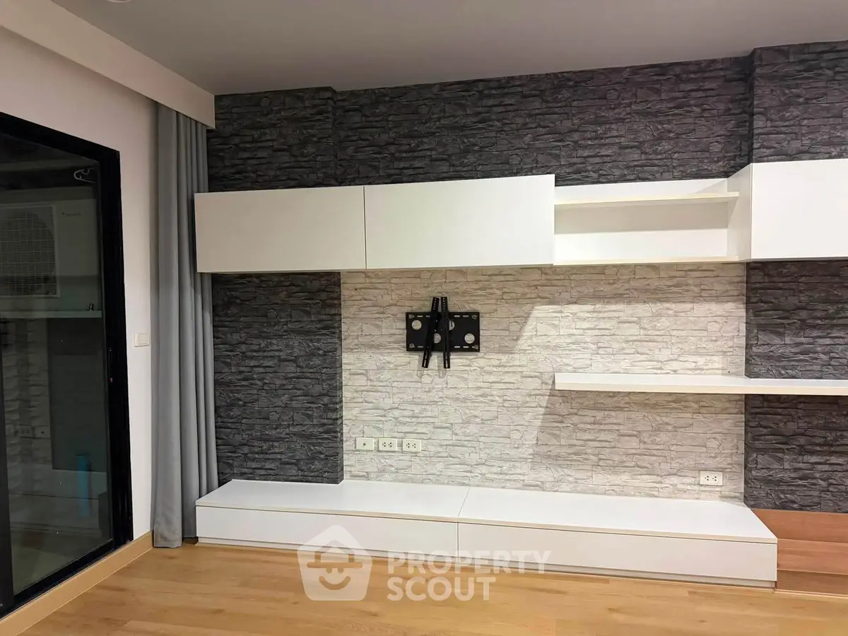 Modern living room with sleek white cabinetry and stone accent wall, perfect for stylish urban living.