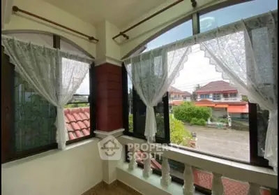 Charming balcony with lace curtains and street view in suburban home.