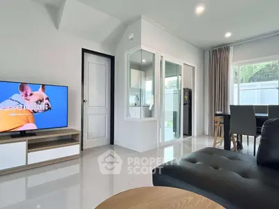 Modern living room with sleek furniture and large TV, open to dining area and kitchen.