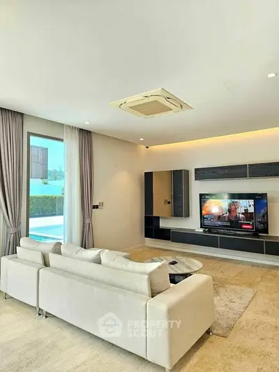 Luxurious living room with modern decor and large TV, perfect for relaxation and entertainment.