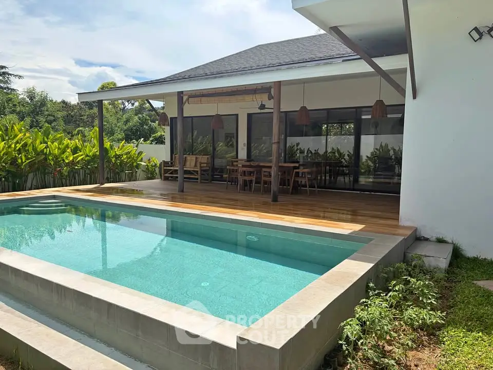 Luxurious modern villa with private pool and spacious outdoor deck, surrounded by lush greenery.