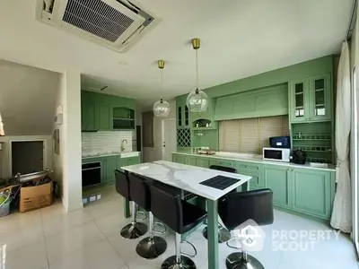 Spacious modern kitchen with green cabinetry and island seating