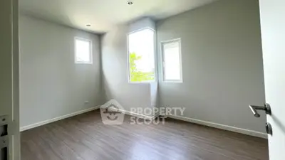 Spacious empty room with large windows and wooden flooring, perfect for customization.