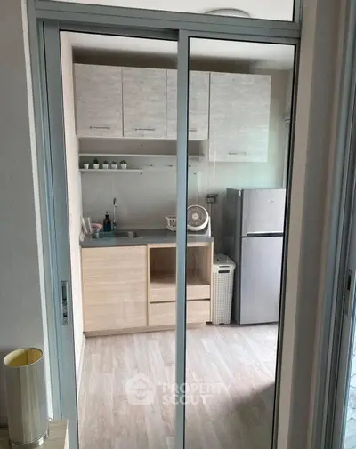 Modern compact kitchen with sleek cabinetry and stainless steel fridge