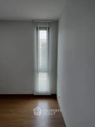 Minimalist room with tall window and wooden floor, perfect for modern living.