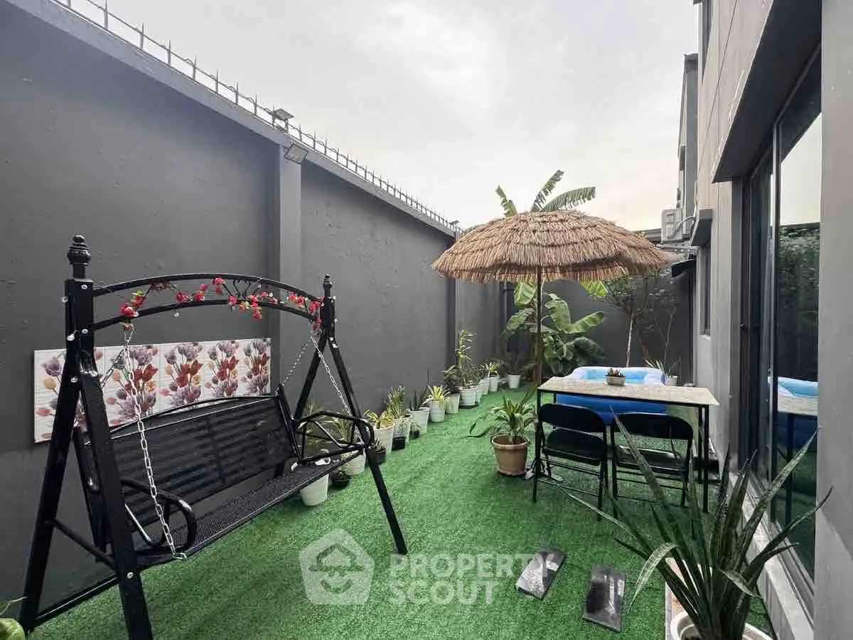 Charming garden patio with swing and tropical decor, perfect for relaxation and outdoor dining.
