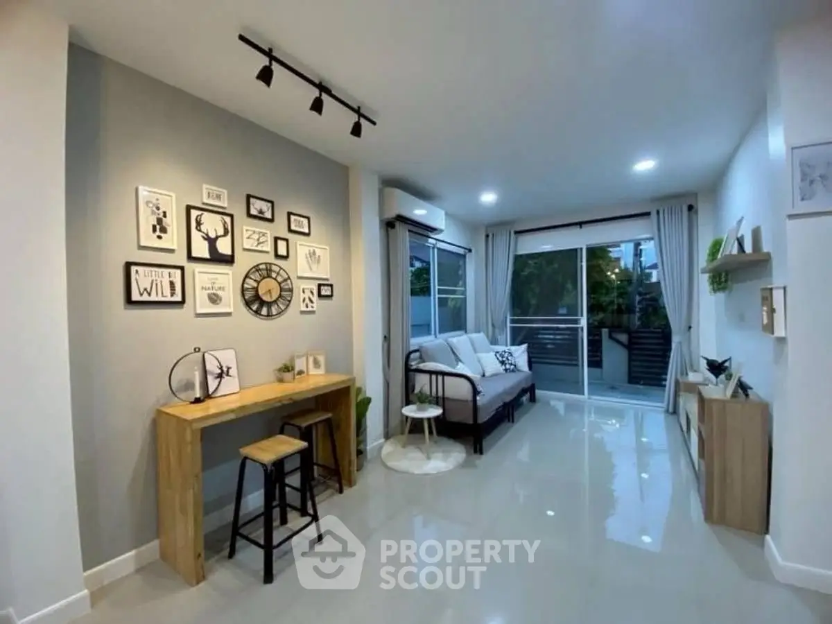 Modern living room with stylish decor and large windows opening to a balcony.