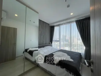 Modern bedroom with city view, featuring large mirrored wardrobe and cozy bedding.