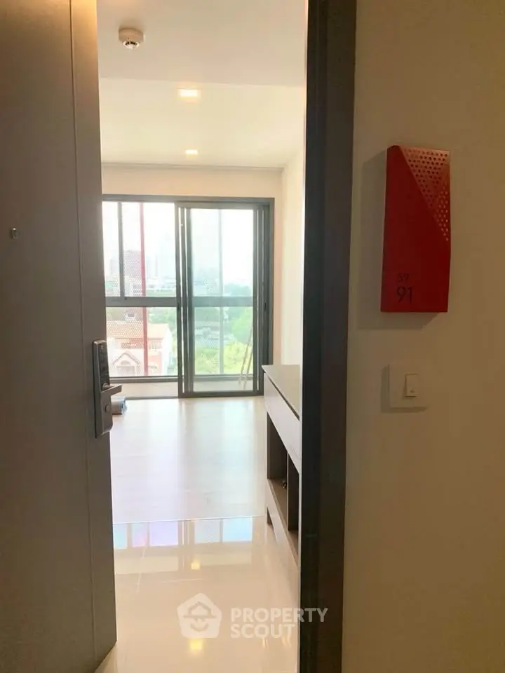Modern apartment entrance with bright living area and large windows offering city views.
