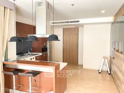 Modern kitchen with sleek wooden cabinetry and stylish bar stools in a contemporary apartment.