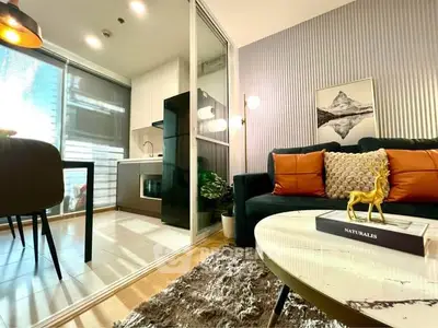 Modern living room with open kitchen, stylish decor, and natural light.