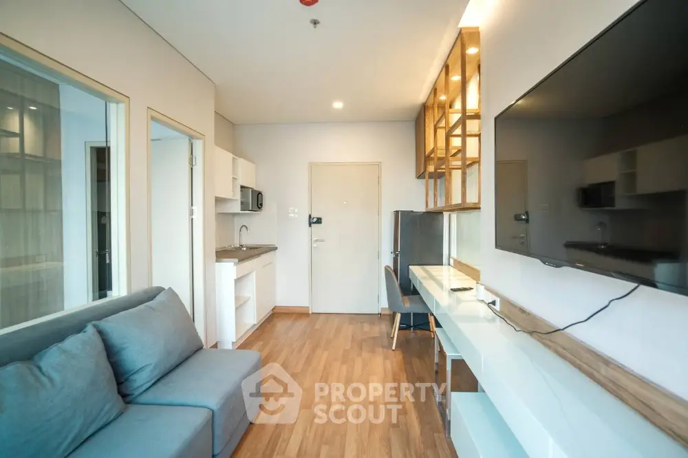 Modern living room with sleek furniture and open layout, featuring a large wall-mounted TV and stylish decor.