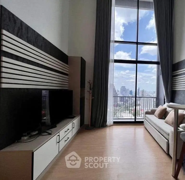 Modern living room with high ceilings and city view through large windows.