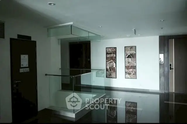 Modern apartment hallway with sleek glass railing and stylish wall art.