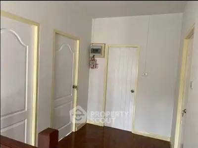Minimalist hallway with white doors and wooden flooring in a modern home.