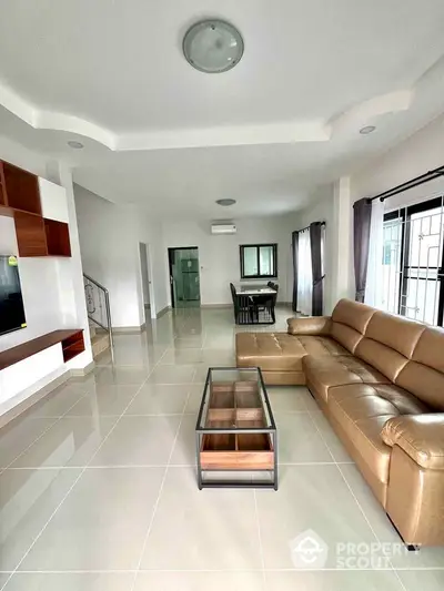 Spacious modern living room with elegant leather sofa and glass coffee table in open layout.