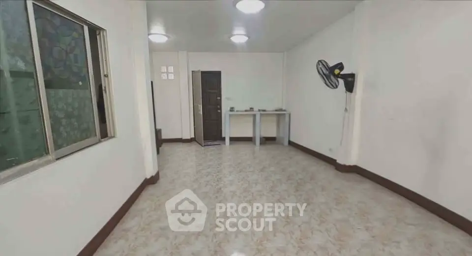Spacious unfurnished room with tiled flooring and wall-mounted fan, ideal for customization.
