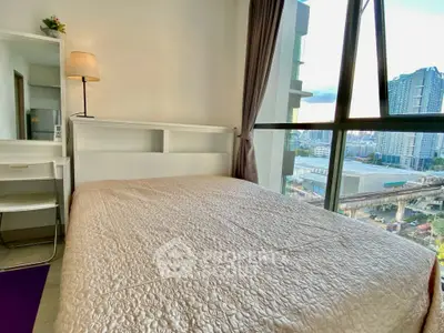 Cozy bedroom with large window offering stunning city view in modern apartment.
