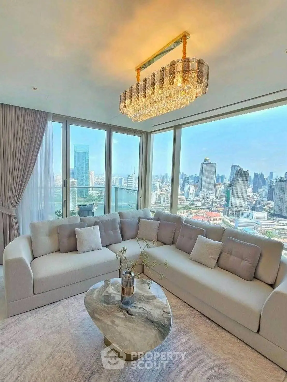 Luxurious living room with panoramic city view and elegant chandelier.