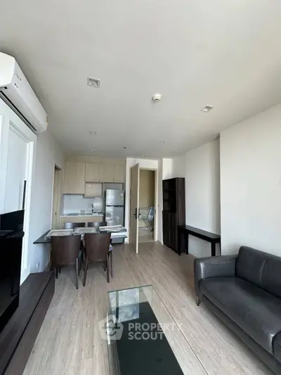 Modern living room with open kitchen, sleek furniture, and natural light.