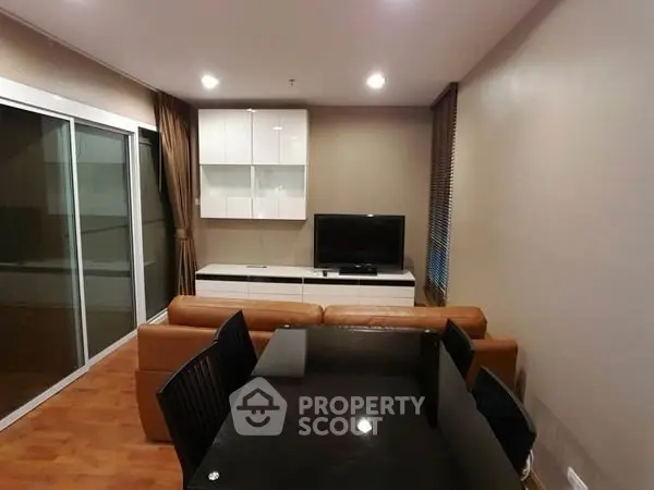 Modern living room with sleek furniture and large glass doors leading to a balcony.