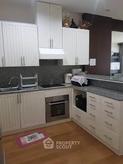 Modern kitchen with sleek cabinetry and built-in oven in a stylish apartment.