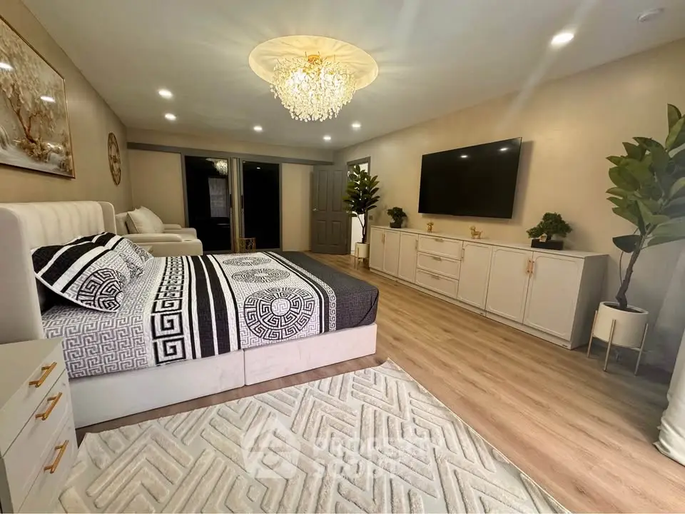 Luxurious bedroom with elegant decor, featuring a plush bed, stylish chandelier, and modern entertainment setup.
