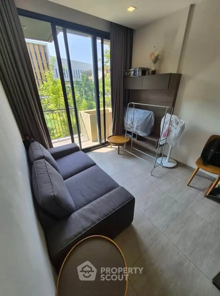 Cozy living room with modern sofa and large windows overlooking greenery, perfect for relaxation.