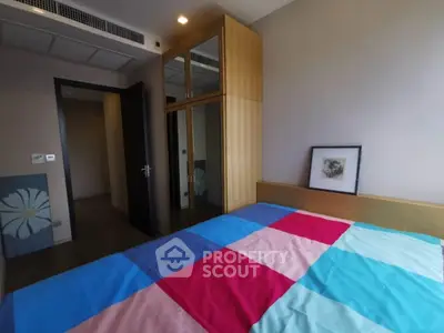 Cozy bedroom with colorful bedding and mirrored wardrobe in modern apartment.