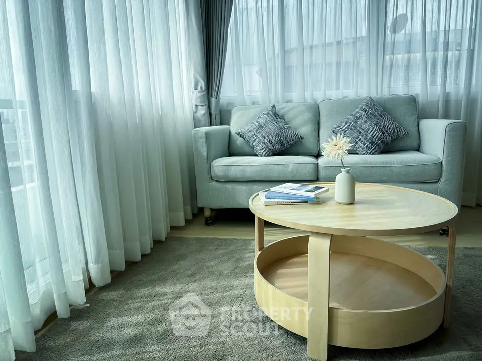 Elegant living room with cozy sofa and stylish coffee table by large windows.