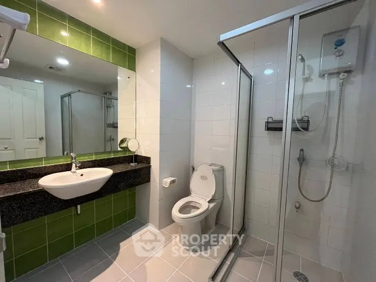 Modern bathroom with glass shower and green tile accents