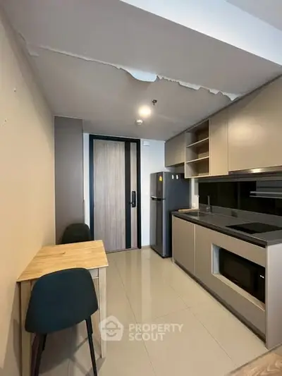 Modern compact kitchen with sleek cabinetry and dining area in a cozy apartment setting.