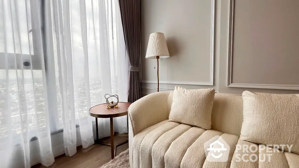 Elegant living room with plush sofa and panoramic city view through large windows.