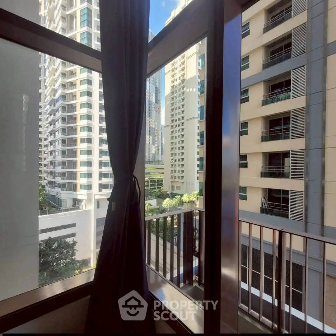 Stunning urban view from a high-rise apartment window with modern buildings.