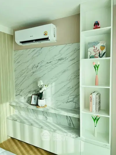 Modern living room with marble accents and built-in shelving, featuring stylish decor and air conditioning.
