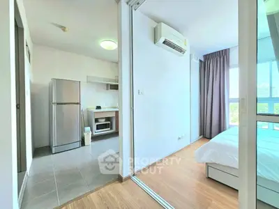 Modern apartment interior with kitchen and bedroom, featuring sleek appliances and natural light.