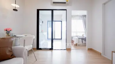 Modern apartment interior with open layout, featuring dining area and bedroom with natural light.