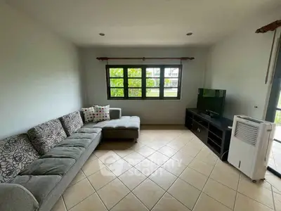 Spacious living room with sectional sofa and TV, featuring large window for natural light.