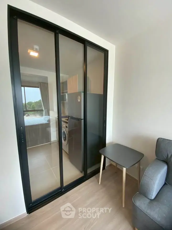 Modern apartment with sliding glass doors leading to a compact kitchen featuring a washing machine.