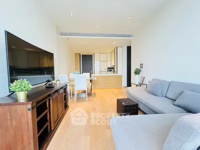 Modern living room with open kitchen, stylish furniture, and wooden flooring in a contemporary apartment.