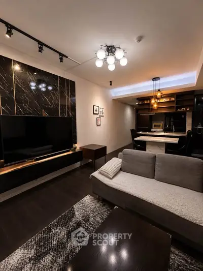 Modern living room with sleek design, featuring a large TV, stylish lighting, and cozy seating area.