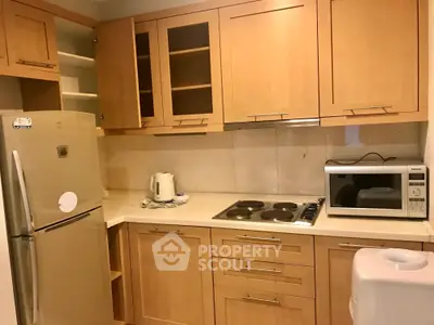 Charming kitchen with wooden cabinets, modern appliances, and sleek countertop in cozy apartment.