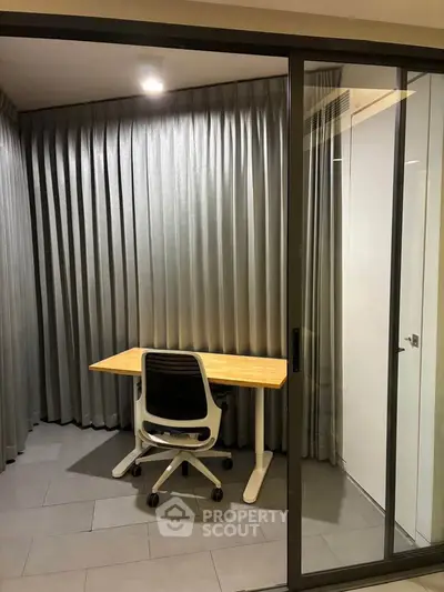 Modern study room with sleek desk and chair, enclosed by glass sliding doors and elegant curtains.