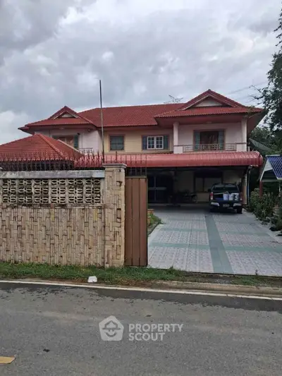 Charming two-story house with red roof and spacious driveway in a serene neighborhood.