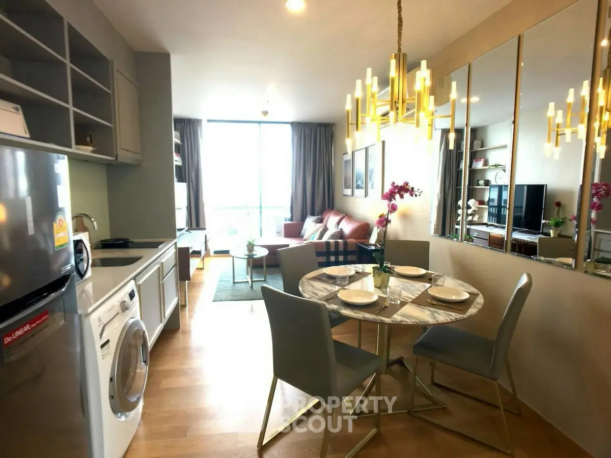Modern open-plan kitchen and living room with elegant chandelier and stylish decor.