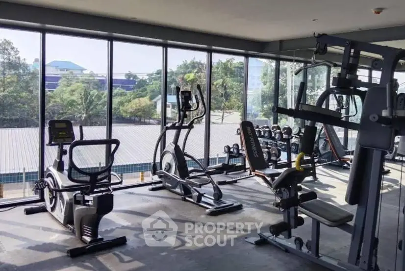 Spacious gym with modern equipment and panoramic windows offering scenic views.