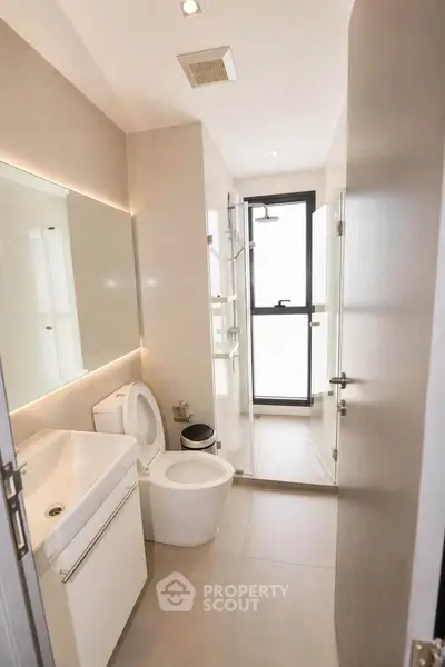 Modern bathroom with sleek fixtures and large glass shower in a contemporary apartment.