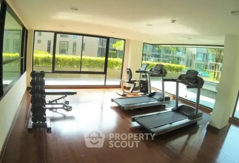 Modern gym with treadmills and weights in a bright apartment complex.